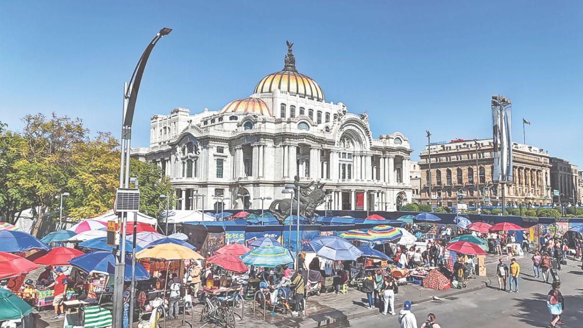 Escenario. Sombrillas de distintos colores y gran variedad de puestos sobresalen de entre las estructuras de metal; algunos capitalinos caminan por debajo de la acera debido al poco espacio para transitar.