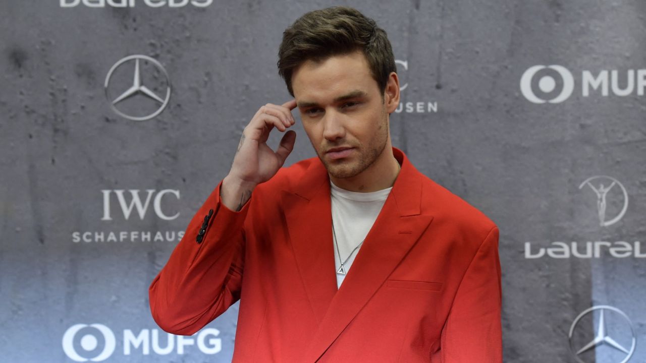 Liam Payne posando en alfombra roja portando un traje naranja. 