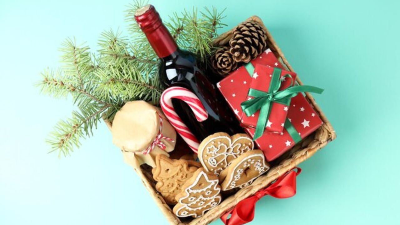 Arcón navideño con galletas, botella de vino, conservas, un regalo envuelto en papel rojo, piñas, ramas de pino y un bastón de caramelo.