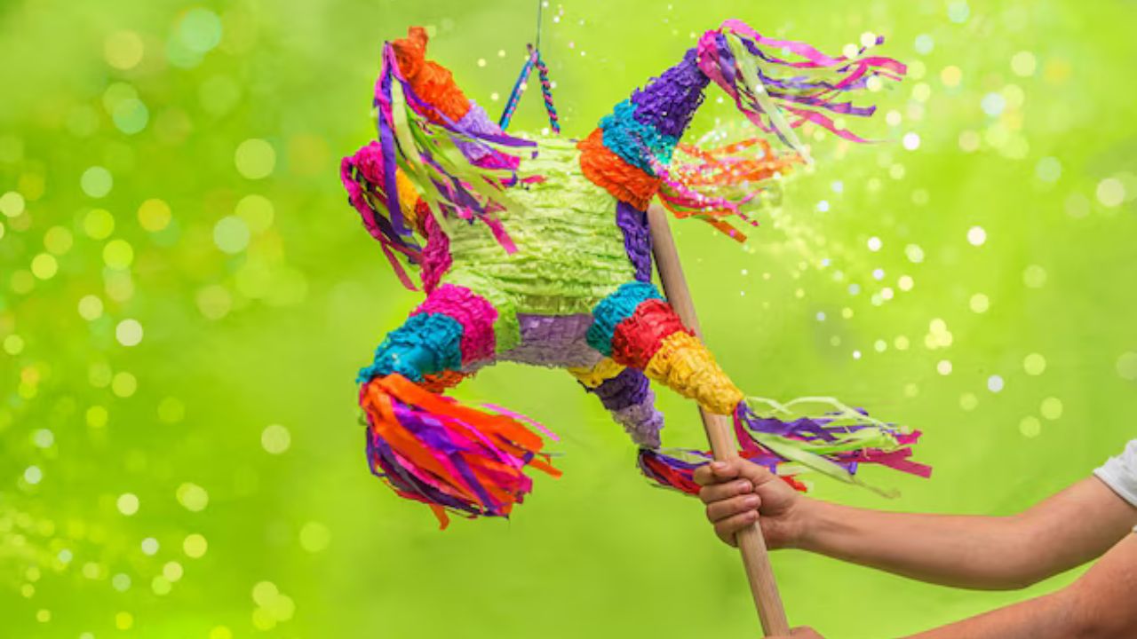 Persona sosteniendo un palo que golpea una piñata de siete picos.