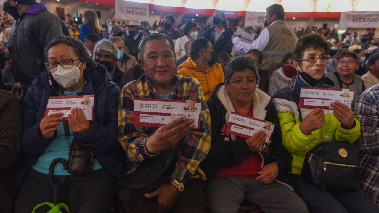 Adultos mayores sosteniendo un sobre que contiene la tarjeta donde se les deposita la Pensión Bienestar