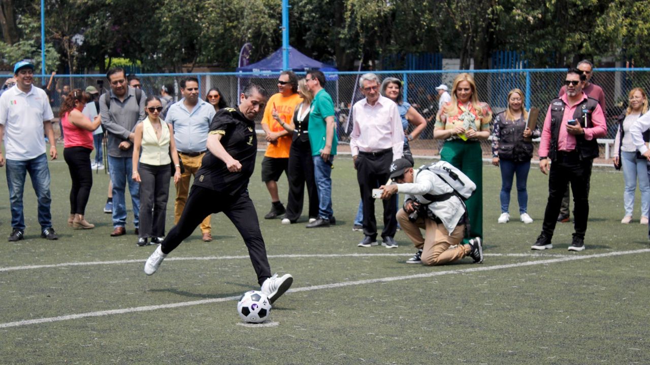 Con el tiro de un penalty, el Alcalde de Coyoacán participa en un concurso de fútbol con el que se promueve acercar a la niñez al deporte.