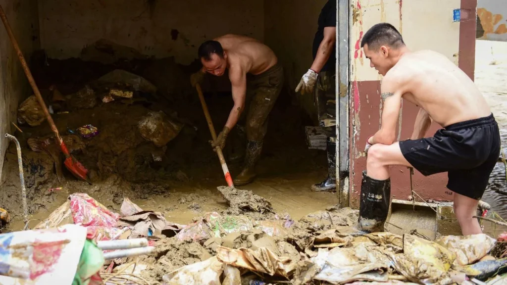 Personas limpian el lodo en una zona afectada por las inundaciones en el suroeste de China