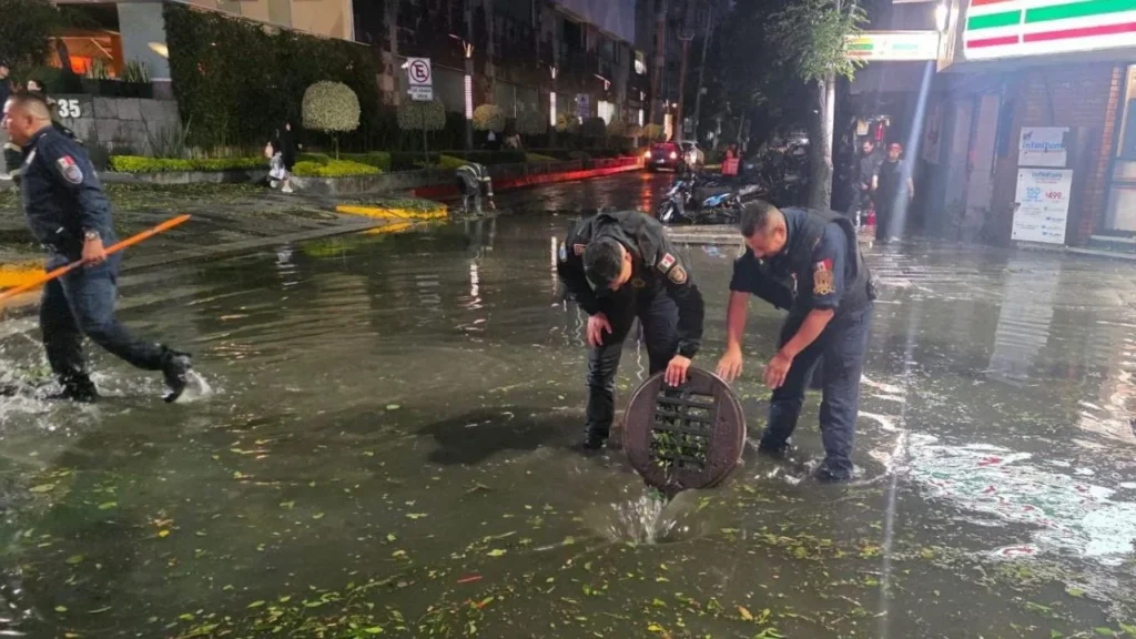 Policías de la SSC realizan el destape de coladeras y retiro de basura, para evitar encharcamientos en la avenida Insurgentes Sur y la calle Yosemit, en la colonia Nápoles, gtras fuertes lluvias y granizo