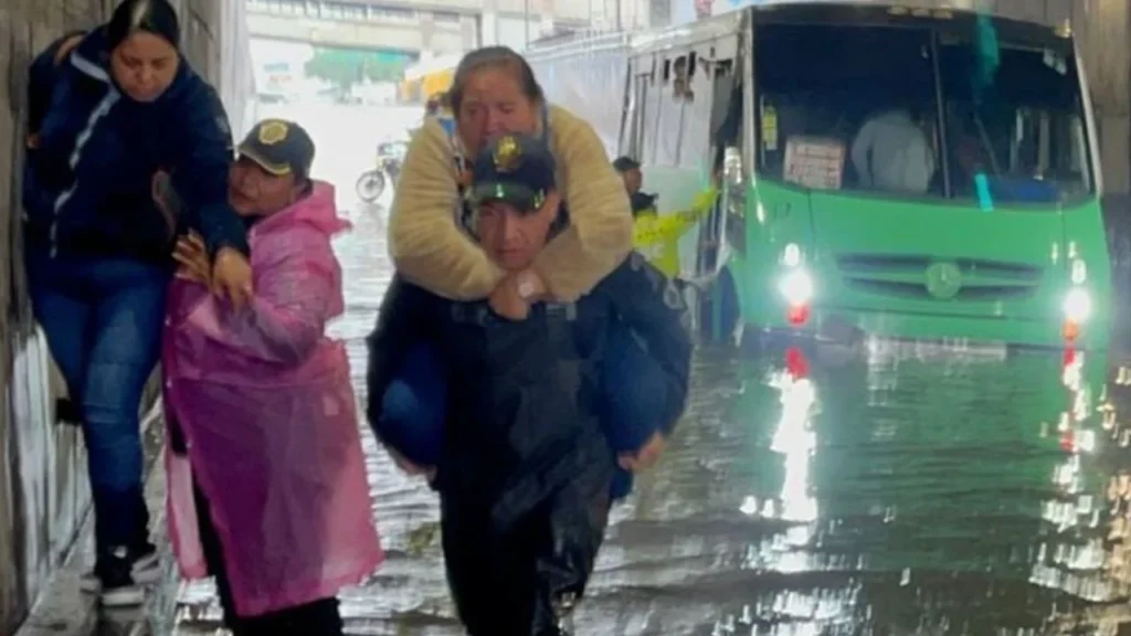 Ayuda. Policías capitalinos cargaron a 63 pasajeros de un autobús que se quedó varado en Iztacalco tras las inundaciones generadas por las fuertes lluvias
