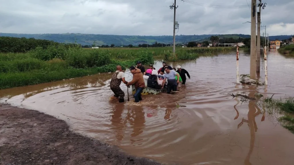 Habitantes de Tototlán caminan entre las aguas que dejaron las precipitaciones.