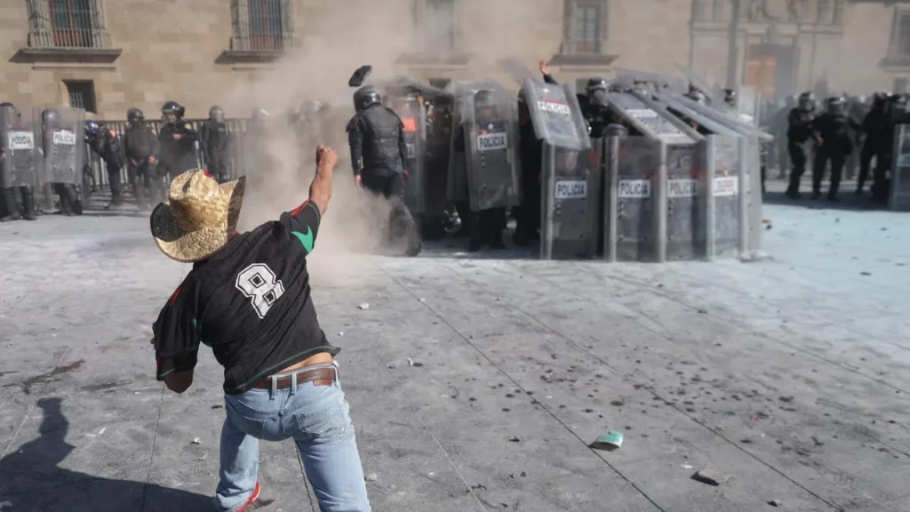 Ante la mayoría de vallas derribadas, la policía forma un muro de escudos y avanza para alejar a los manifestantes de Palacio.
