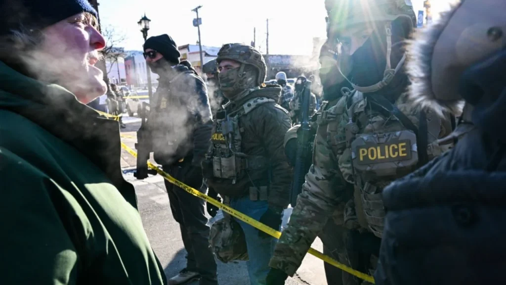 Un hombre habla con agentes federales mientras los manifestantes se reúnen cerca del lugar donde, según las autoridades estatales y locales, un hombre fue baleado por agentes federales esa misma mañana en Minneapolis, Minnesota, el 24 de enero de 2026