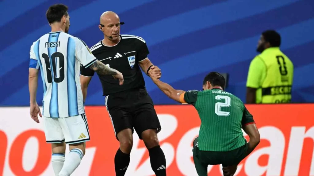 El árbitro ayuda al jugador de Argelia tras la falta de Messi.