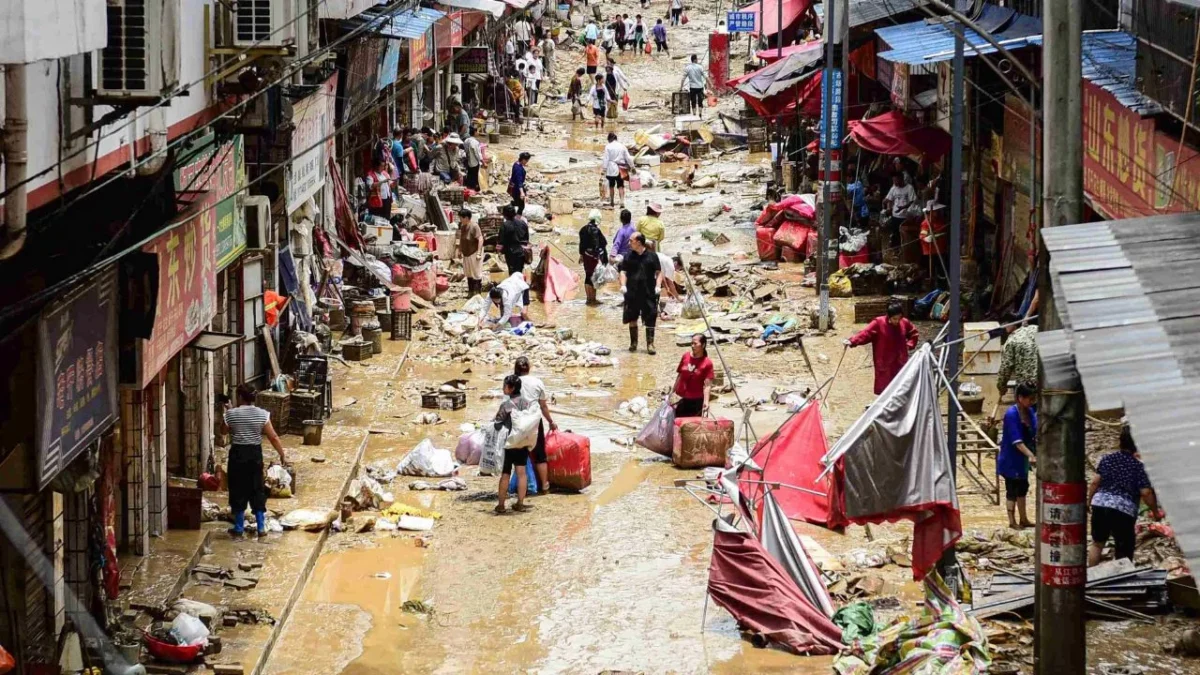 Personas caminan con sus pertenencias en una zona inundada en Congjiang, provincia de Guizhou, suroeste de China