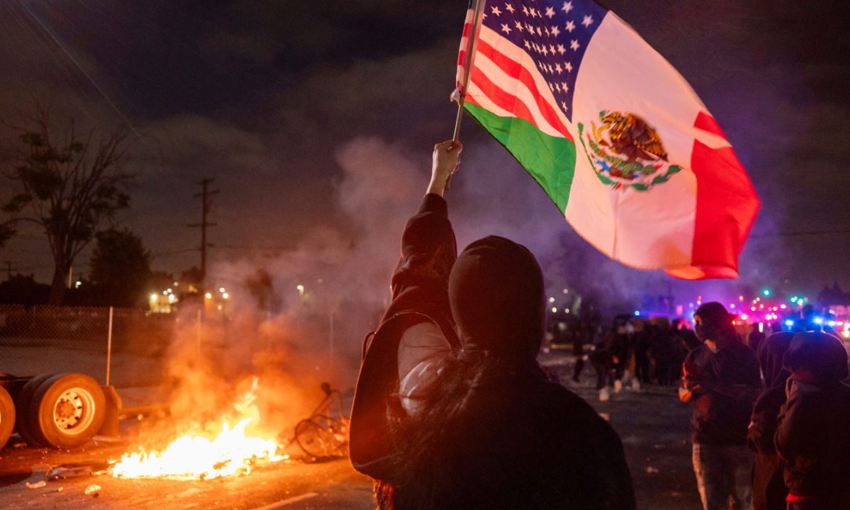 Aunque hay operativos, las manifestaciones siguen. Fernando Delgado, joven hispano con una bandera mexicana frente a un vehículo calcinado, lo dice claro: “Somos trabajadores, no criminales.”