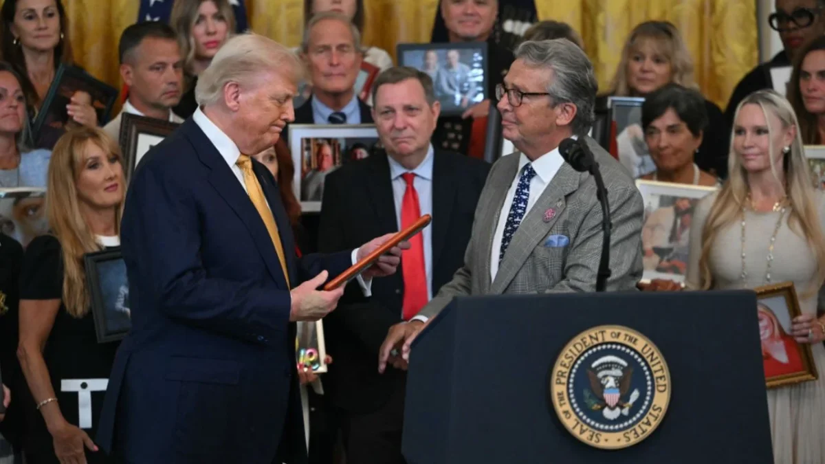 El mandatario de la Casa Blanca mira una foto en la que un hombre que perdió a su hijo a causa del fentanilo habla antes de la firma de la ley.