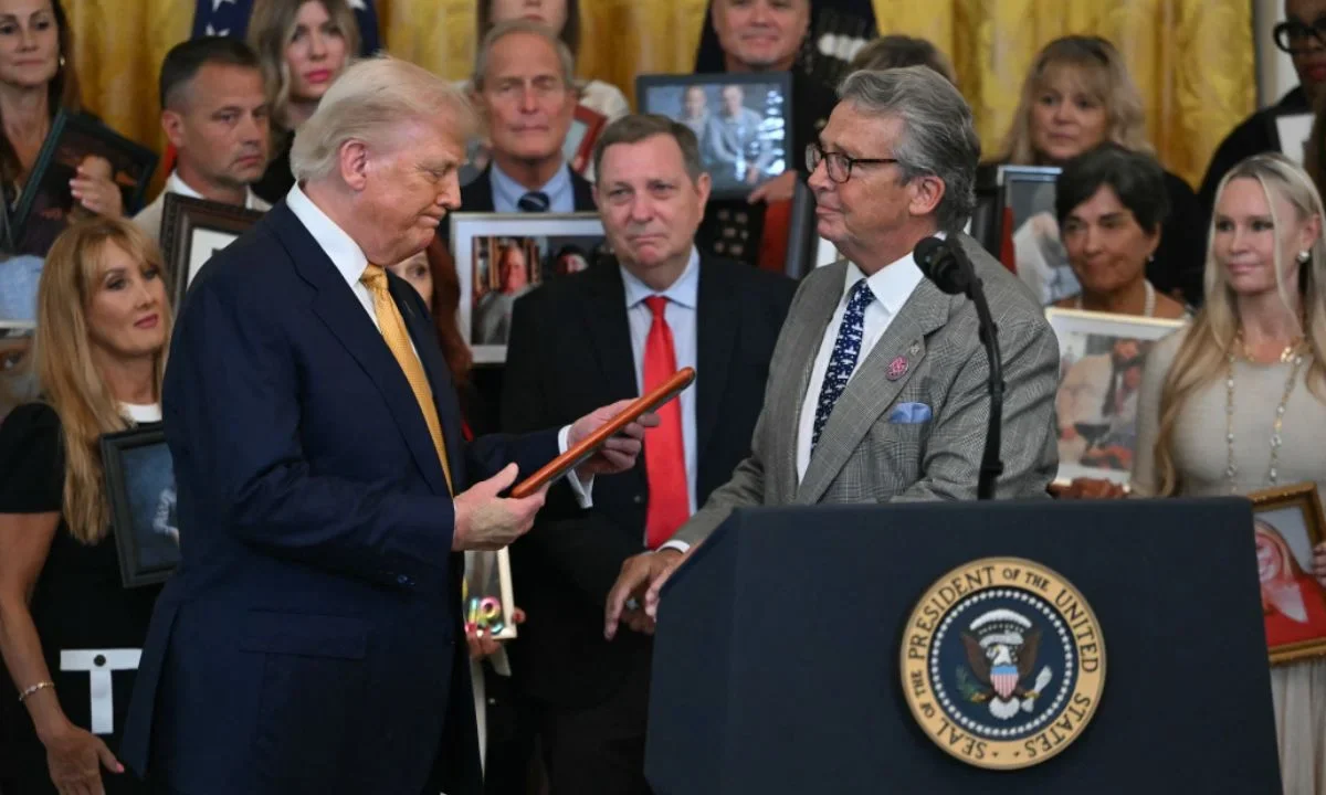 El mandatario de la Casa Blanca mira una foto en la que un hombre que perdió a su hijo a causa del fentanilo habla antes de la firma de la ley.