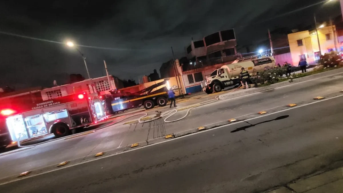 Bomberos de la Ciudad de México trabajan para liberar la pipa de Pemex caída en un socavón en Iztacalco.