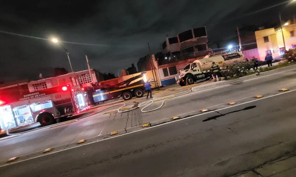 Bomberos de la Ciudad de México trabajan para liberar la pipa de Pemex caída en un socavón en Iztacalco.