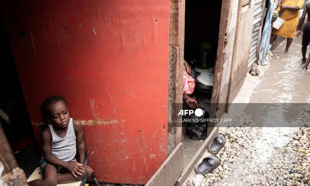 A child looks out at a flooded camp for displaced people following Hurricane Melissa in Port-au-Prince on October 29, 2025.