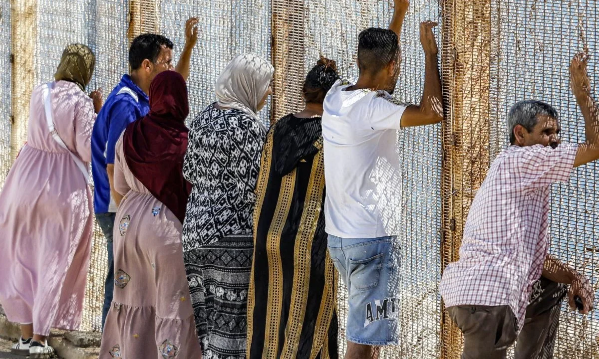Familiares y amigos esperan junto a una valla coronada con alambre de púas para el regreso de personas que habían cruzado previamente al enclave de Ceuta