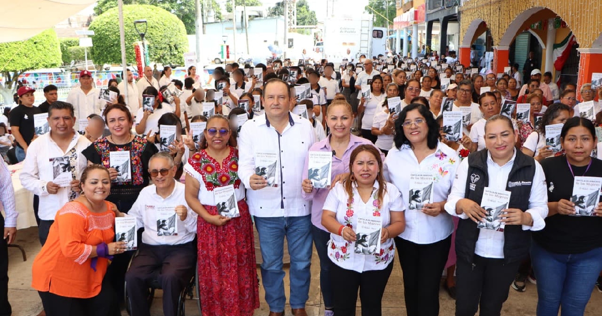 Funcionarios y mujeres sosteniendo la cartilla de derechos 