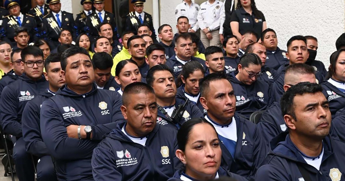 Fotografía en plano medio que muestra a un grupo de elementos de la Secretaría de Seguridad Ciudadana (SSC) de la Ciudad de México sentados y atentos durante un evento ceremonial. Vestidos con chaquetas deportivas oscuras de la SSC con el escudo de la institución y del Gobierno de la Ciudad de México, los policías representan a los participantes de la competencia