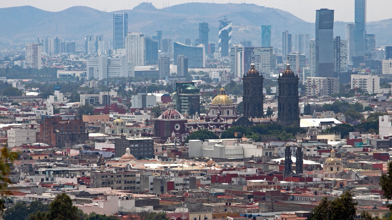 Vista panorámica del Centro Histórico de Puebla con la Catedral en primer plano y los rascacielos de la ciudad al fondo.