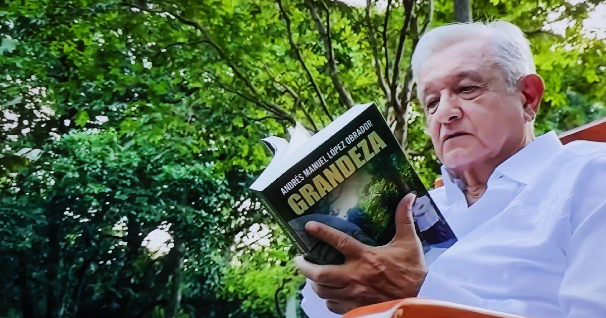 Andrés Manuel López Obrador en su quinta en Palenque, Chiapas, durante su retiro político. Aparece sentado al aire libre con el follaje verde de fondo, luciendo una guayabera o camisa blanca de manga larga. Sostiene con ambas manos y lee atentamente un ejemplar de su libro