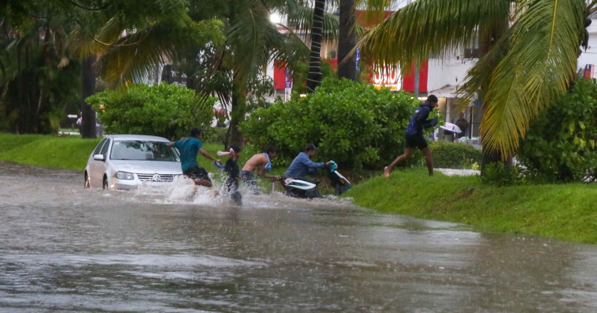 Una avenida inundada con personas intentando ponerse bajo resguardo