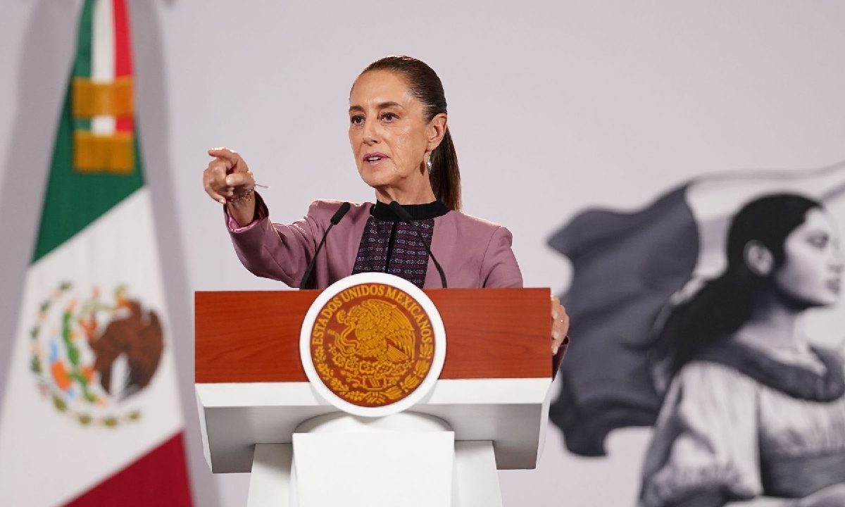 presidenta claudia sheinbaum en el estrado de la mañanera señalando al costado izquierdo