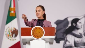 presidenta claudia sheinbaum en el estrado de la mañanera señalando al costado izquierdo