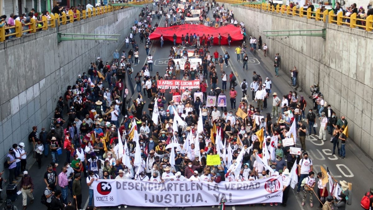 Manifestantes marchando en el bajo puente de eje central con una lona blanca al frente