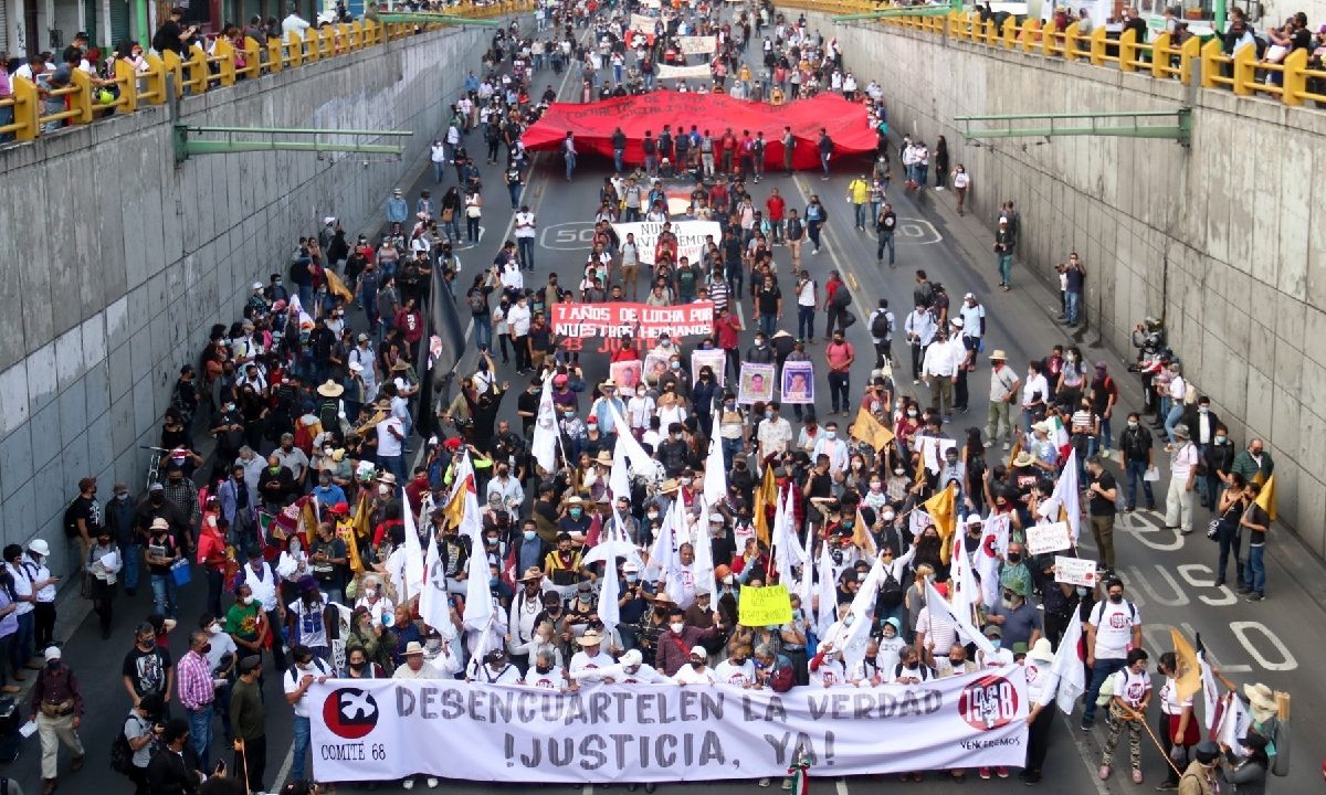 Manifestantes marchando en el bajo puente de eje central con una lona blanca al frente