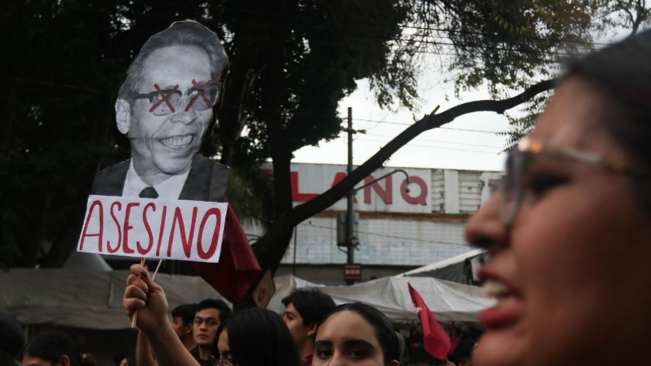 Una mujer sostiene una pancarta con la cara de Díaz Ordaz con la leyenda asesino 