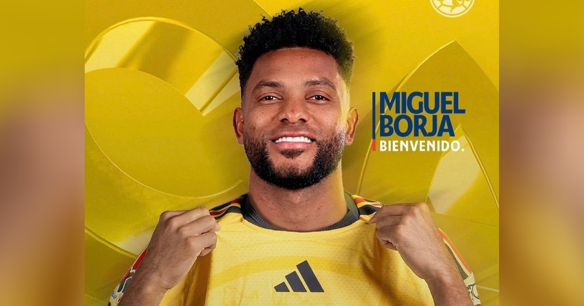 Miguel Borja luciendo la camiseta amarilla del Club América con detalles de Adidas. El jugador aparece sonriendo a la cámara mientras sostiene el cuello de su camiseta con ambas manos. Del lado derecho se incluye la tipografía institucional con la leyenda «MIGUEL BORJA BIENVENIDO.»