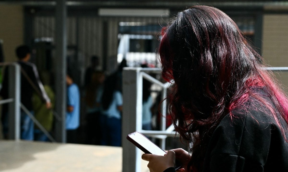 Una joven con la cara cubierta por su cabello observa su celular