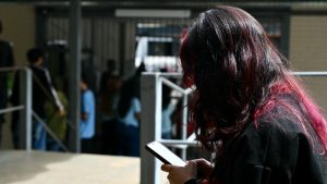 Una joven con la cara cubierta por su cabello observa su celular